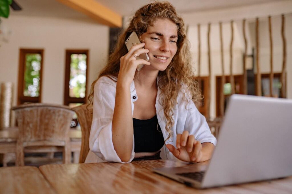 a lady making a phone call while looking at her laptop